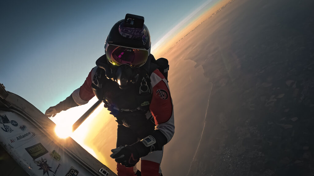 Un parachutiste anonyme s'élançant pour un saut en chute libre depuis la porte d'un avion, surplombant les paysages côtiers de la Vendée.